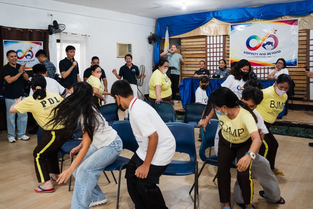 Mothers and children rush for chairs during a game of Trip to Jerusalem in a hall decorated with the Foundation’s banners.